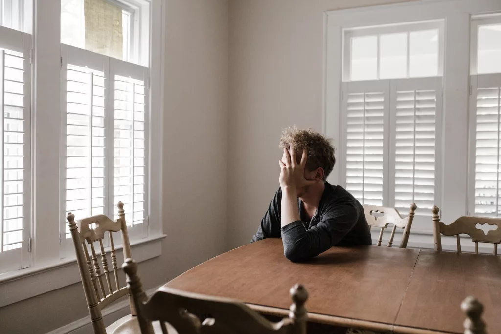 A man sits at a table with his head in his hands 